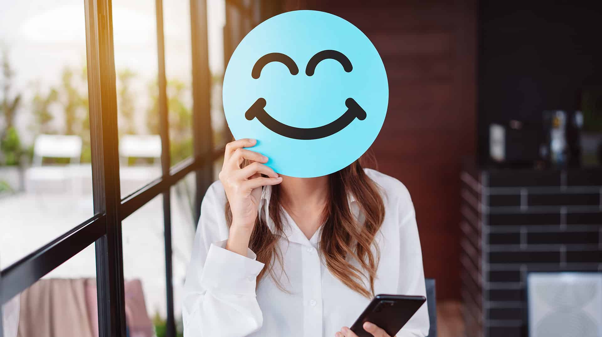 Abbildung Frau mit Smilie-Schild vorm gesicht